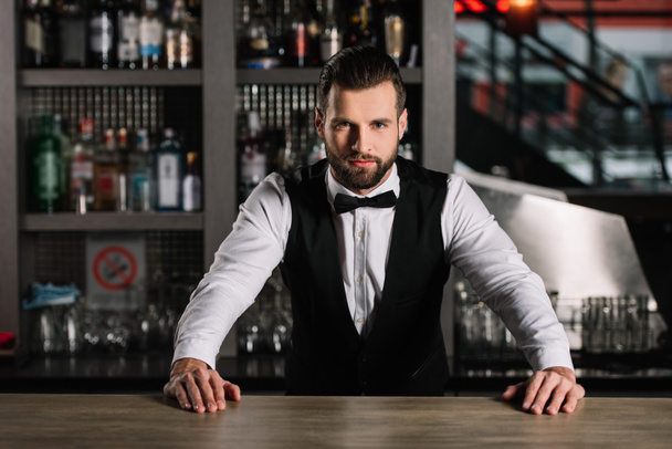 camarero guapo apoyado en el mostrador de bar y mirando a la cámara
 - Foto, imagen