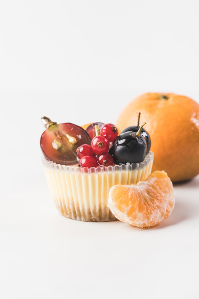 закрыть вид на сладкий кекс с ягодами, фруктами и танжерином рядом изолированы на белом
 - Фото, изображение