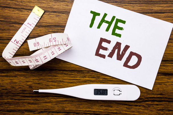 Conceptual hand writing text caption showing The End. Business concept for End Finish Close written on sticky note paper on wood background. Meter and thermometer for fitness subject. - Photo, Image