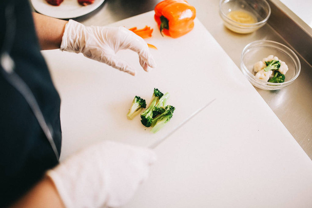 chef hands cut broccoli on a white board - Φωτογραφία, εικόνα