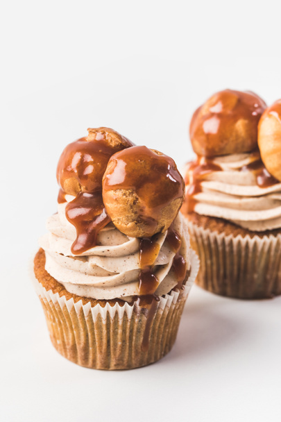 primer plano vista de cupcakes con crema, profiteroles y caramelo aislado en blanco
 - Foto, Imagen