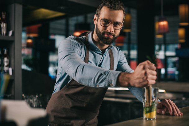 handsome bartender preparing alcohol drink and looking at camera - Φωτογραφία, εικόνα