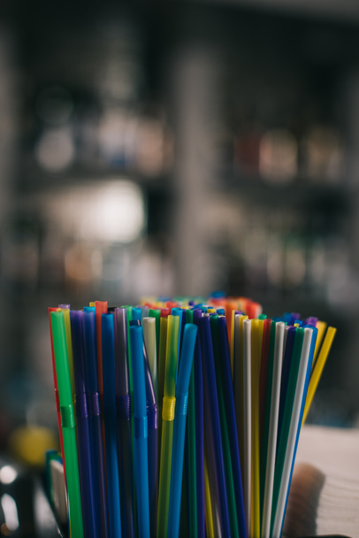 colored plastic straws for drinking on blurred background - Foto, Imagem