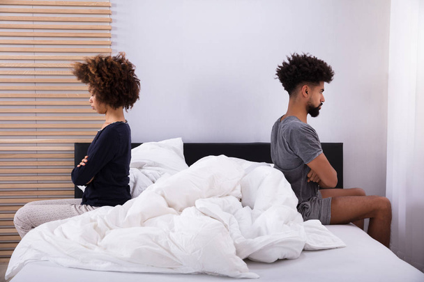 Side View Of Young Couple Sitting On Bed Ignoring Each Other - Foto, Imagen