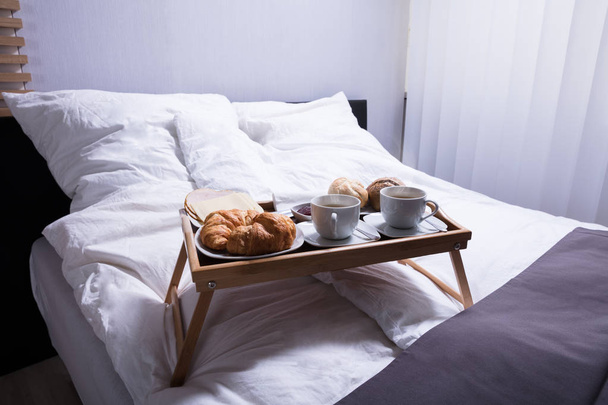 Croissant freschi e tazza di tè a letto a colazione
 - Foto, immagini