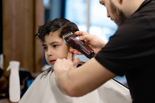 Der Junge wird im Friseursalon geschnitten - Foto, Bild