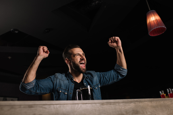 Visitor screaming at bar counter and showing yes gesture while watching football match - Photo, Image