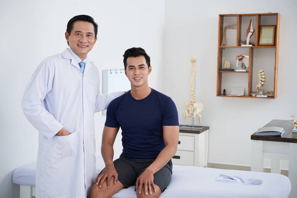 glücklicher vietnamesischer Arzt und sein männlicher Patient - Foto, Bild