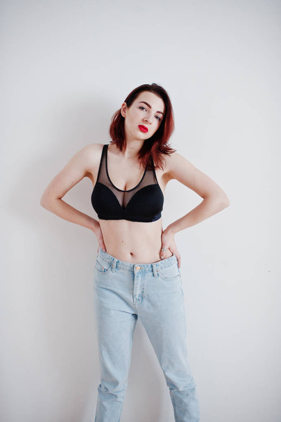 Red haired girl with a big bust on black bra and jeans against w - Foto, afbeelding