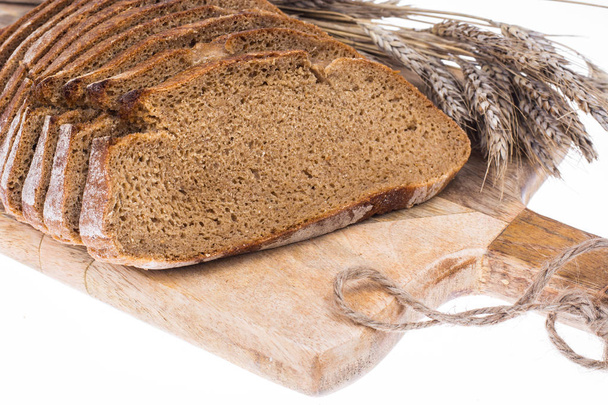 ライ麦パン、キッチンの木の板に粒で耳をスライス - 写真・画像