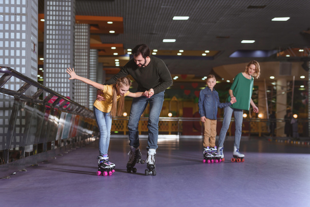 padres y niños patinando juntos en pista de patinaje
 - Foto, Imagen