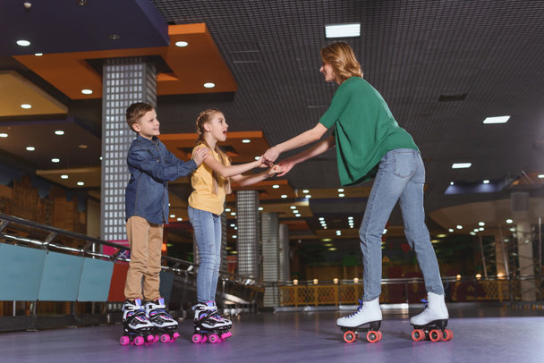 side view of mother and kids skating together on roller rink - Valokuva, kuva