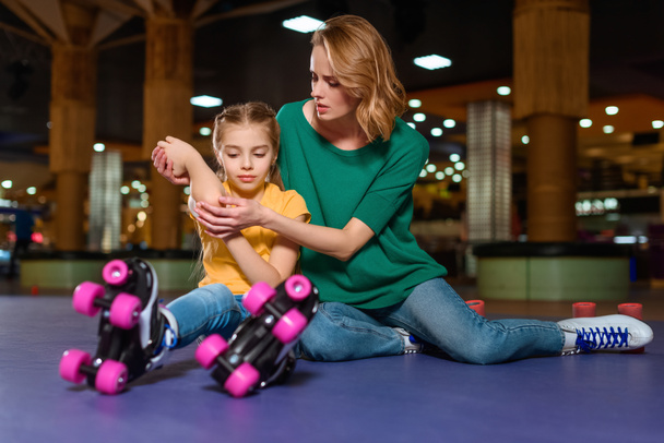 mother cheering up injured daughter on roller rink - Фото, изображение