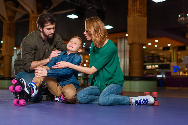 parents appeasing crying son in roller skates on roller rink - 写真・画像