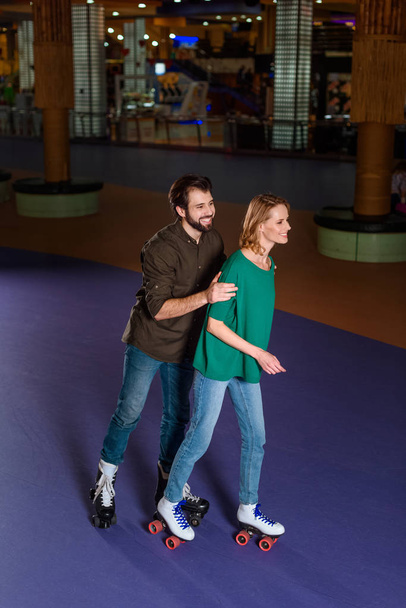 young smiling couple skating together on roller rink - Photo, Image