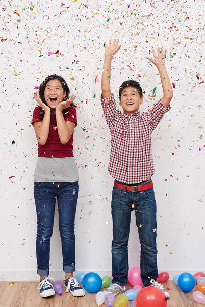 Joyful kids having party with confetti and balloons at home - 写真・画像