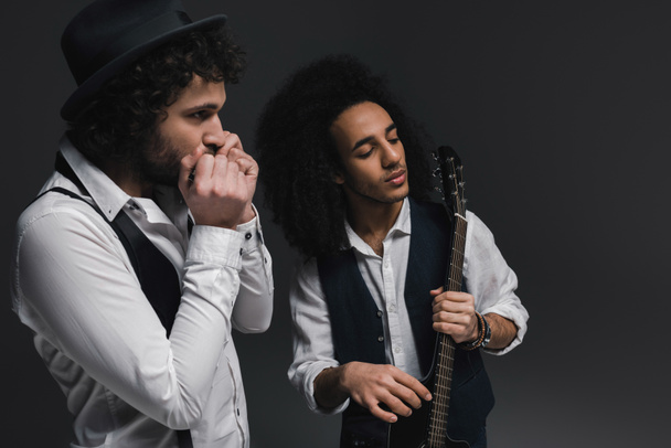 duet van muzikanten spelen van akoestische gitaar en mondharmonica op zwart - Foto, afbeelding