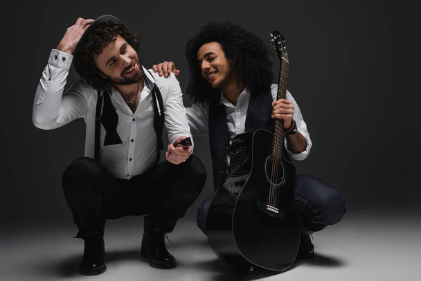 Duett fröhlicher Musiker mit Gitarre und Mundharmonika in der Hocke - Foto, Bild