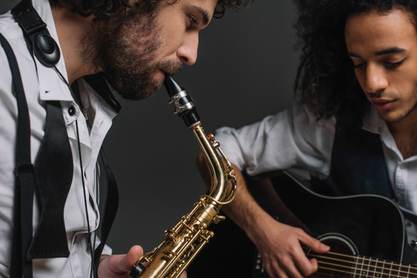 duet of jazzmen playing sax and acoustic guitar on black - Photo, Image