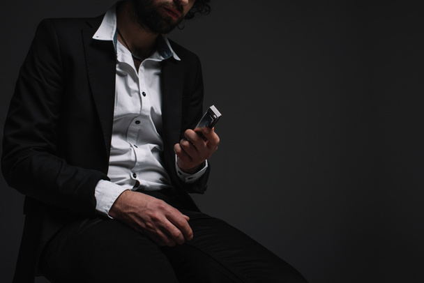 cropped shot of man in suit holding harmonica on black - Photo, Image