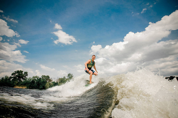 Surfer reitet Wakeboard auf hoher Welle von Motorboot - Foto, Bild