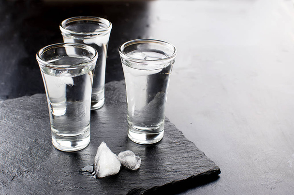 Vodka shots on black table - Фото, изображение