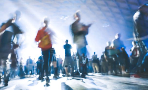 abstrakt verschwommene Menschen, die sich bewegen und tanzen bei Musiknacht Festival Veranstaltung - defokussiertes Bild von Disco Club Party mit Lasershow - Nachtleben Unterhaltungskonzept - azurblauer Kontrast Scheinwerferfilter - Foto, Bild