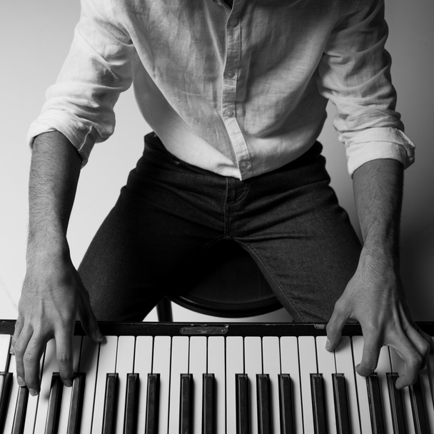 zwart-wit bijgesneden schot van man piano spelen - Foto, afbeelding