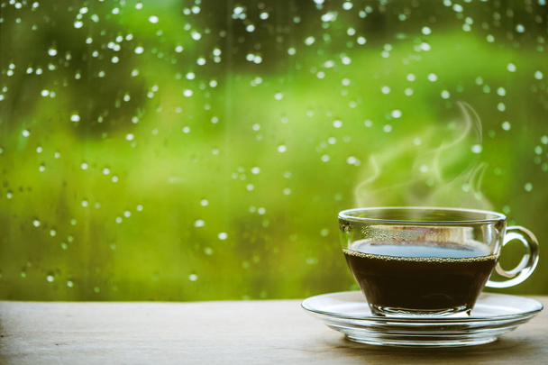 Чашка кави на столі всередині вікна, кава вранці з дощовим днем, розслаблюючі та освіжаючі концепції
. - Фото, зображення