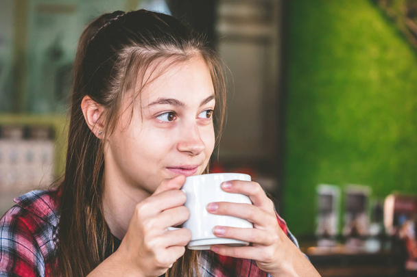 Красивая девушка пьет кофе в кафе, думая и глядя
 - Фото, изображение