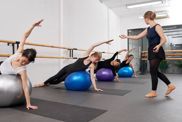 Instrutor olhando como as mulheres realizando exercício em bolas de ajuste
 - Foto, Imagem