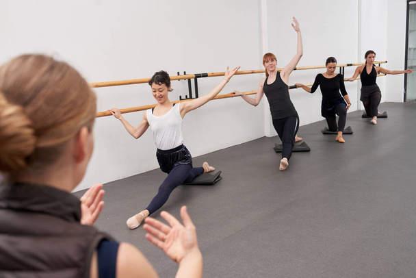 Vrouwen die proberen te doen de splitsingen op ballet klas voor beginners - Foto, afbeelding