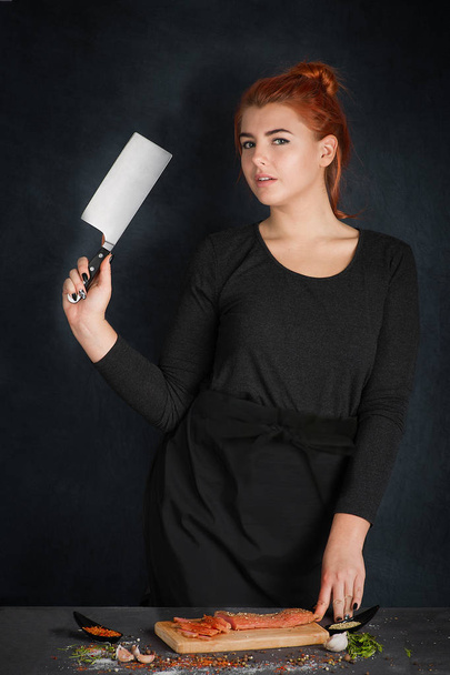 a nő a szakács késsel egy kézzel állni a fekete kötény - Fotó, kép