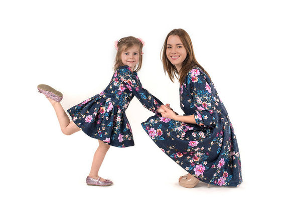 мать с дочерью в одинаковых платьях стоять и улыбаться
 - Фото, изображение