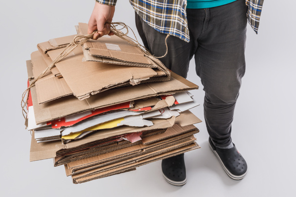 обрізаний знімок людини, що тримає купу складених картонних коробок ізольованих на сірому, концепція переробки
 - Фото, зображення