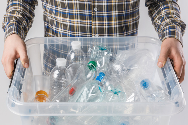 частичное представление человека, держащего контейнер с пластиковыми бутылками в руках изолированы на сером, концепция переработки
 - Фото, изображение