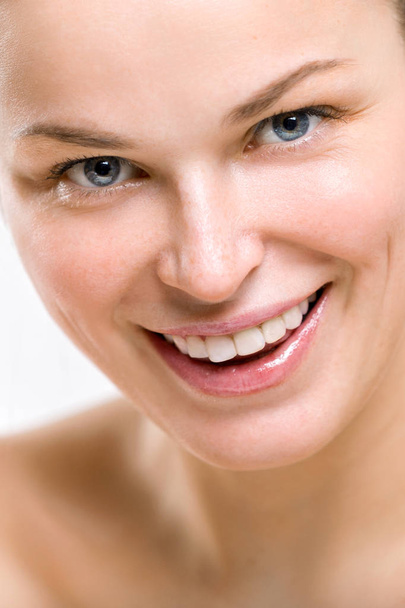 Portret van een mooie jonge lachende vrouw op een lichte achtergrond - Foto, afbeelding