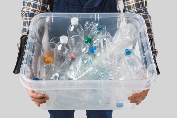 visão parcial do homem segurando recipiente com garrafas de plástico em mãos isoladas em cinza, conceito de reciclagem
 - Foto, Imagem