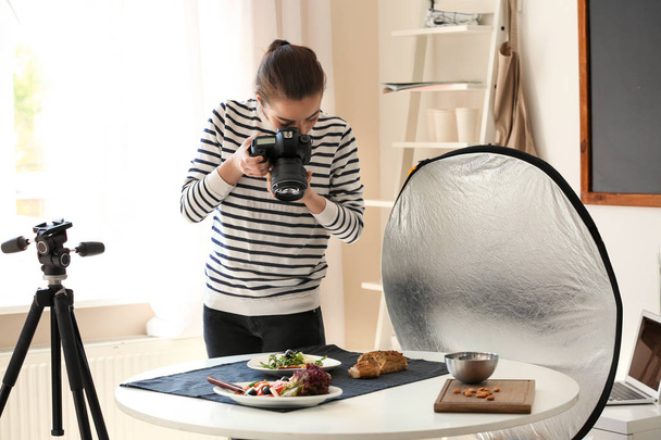 Young woman with professional camera preparing still life composition in photo studio - Foto, Bild