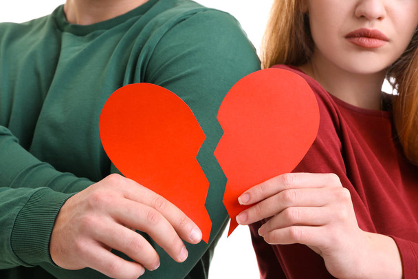 Young couple holding halves of broken heart on white background. Relationship problems - Foto, Imagen