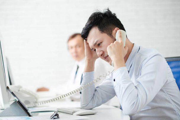 Un joven empresario infeliz contando malas noticias alguien al teléfono
 - Foto, Imagen