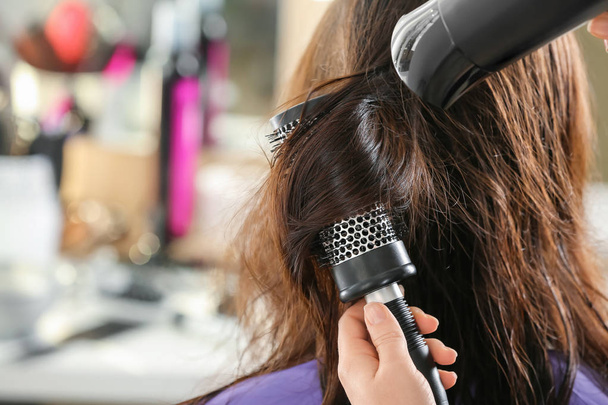 Professional hairdresser drying client's hair in beauty salon - Fotoğraf, Görsel