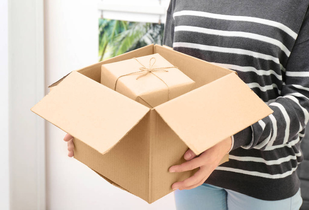Woman holding parcel with gift box at home - Foto, afbeelding