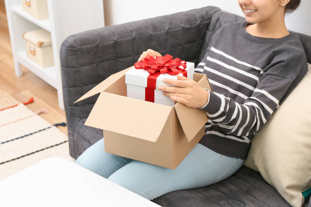 Woman taking gift box out of parcel at home - Fotoğraf, Görsel