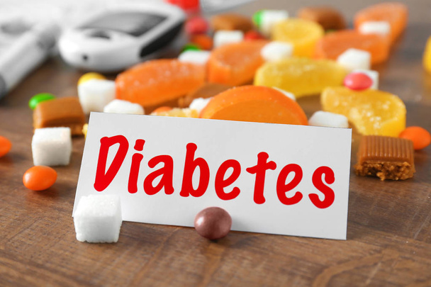 Card with word DIABETES and sweets on table - Foto, Bild