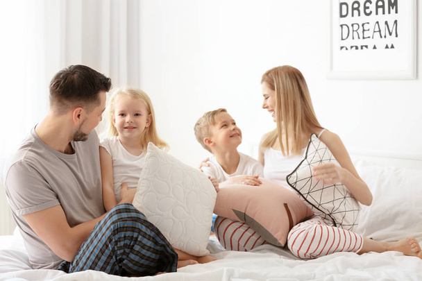 Happy family on bed with soft pillows at home - Фото, зображення