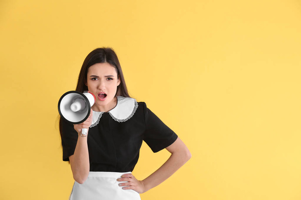 Young chambermaid with megaphone on color background - Foto, Imagem