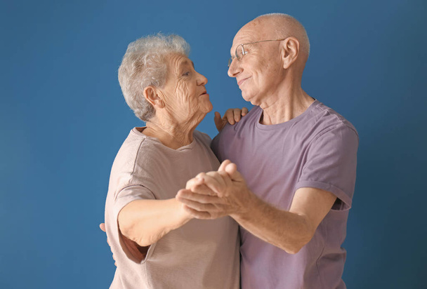 Cute elderly couple dancing against color background - Фото, изображение