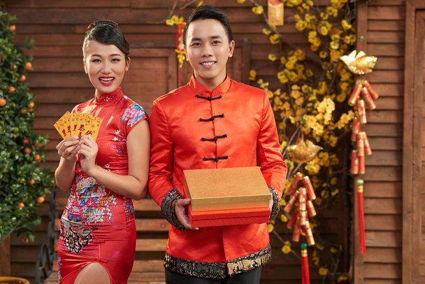 アジア カップル伝統的な衣装を着て、手にベトナムの新年の属性を保持 - 写真・画像