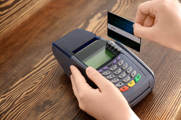 Woman using bank terminal for credit card payment on wooden table - 写真・画像